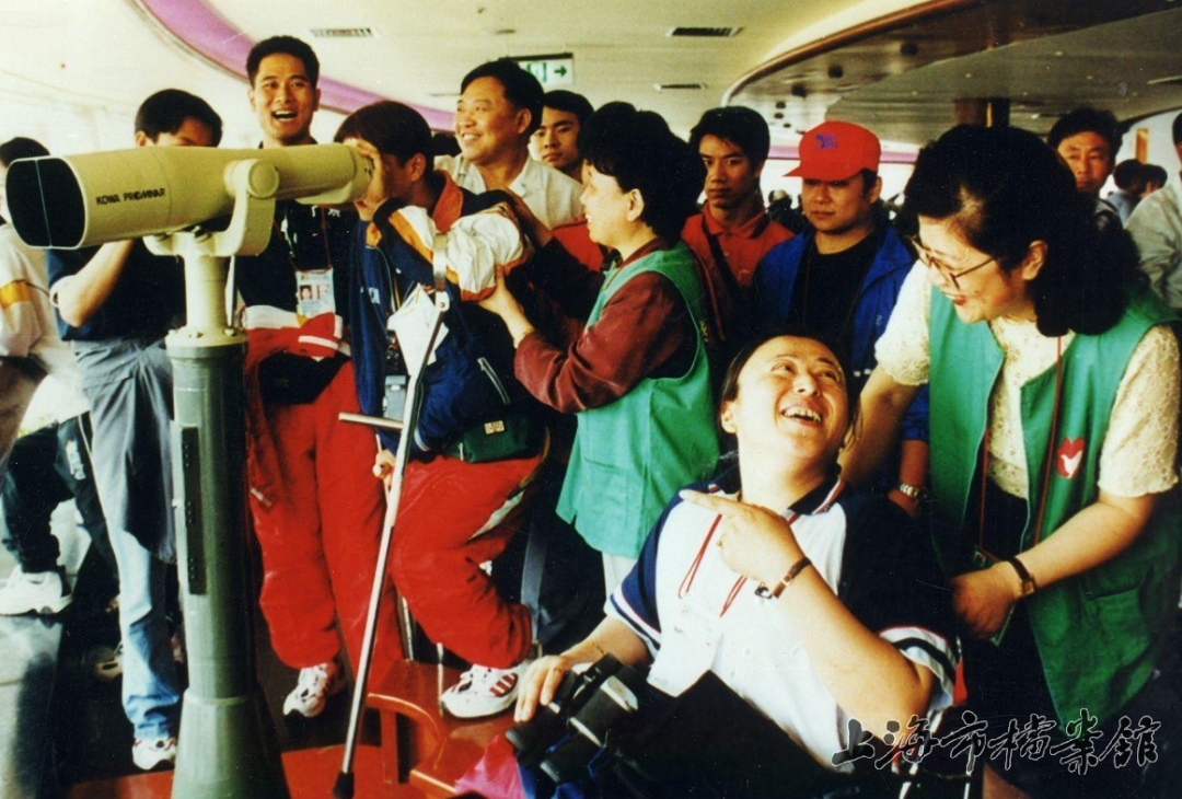 2000年，志愿者帮助残障人士登上东方明珠塔（上海市档案馆藏）